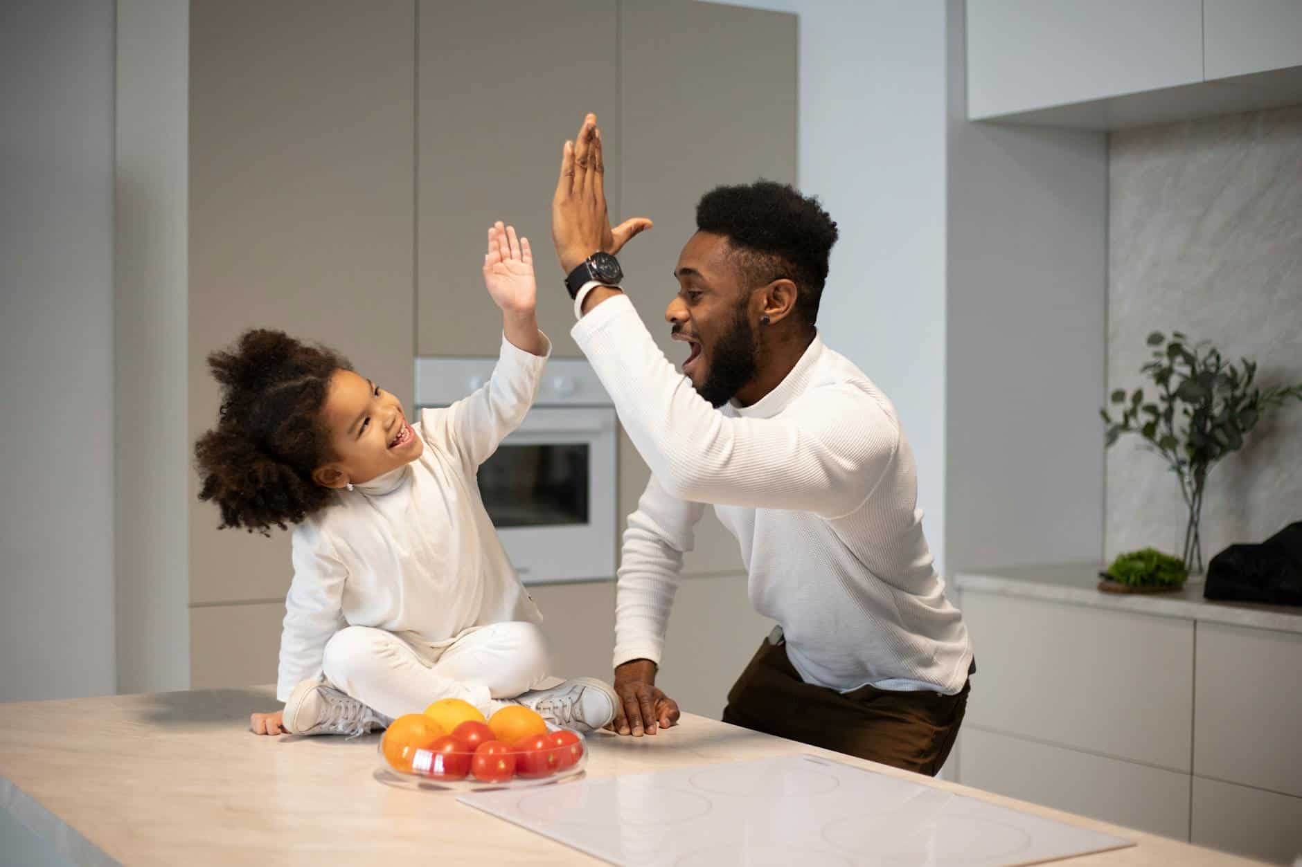 Father and daughter high-fiving, representing positive reinforcement and encouragement.