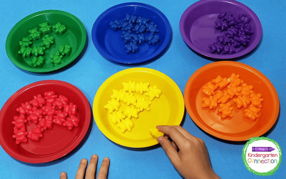 bears sorted in different colors green, blue, purple. red, yellow, orange, There are about 11 bears on each plats and each plate matches the color of the bear that is on it.
