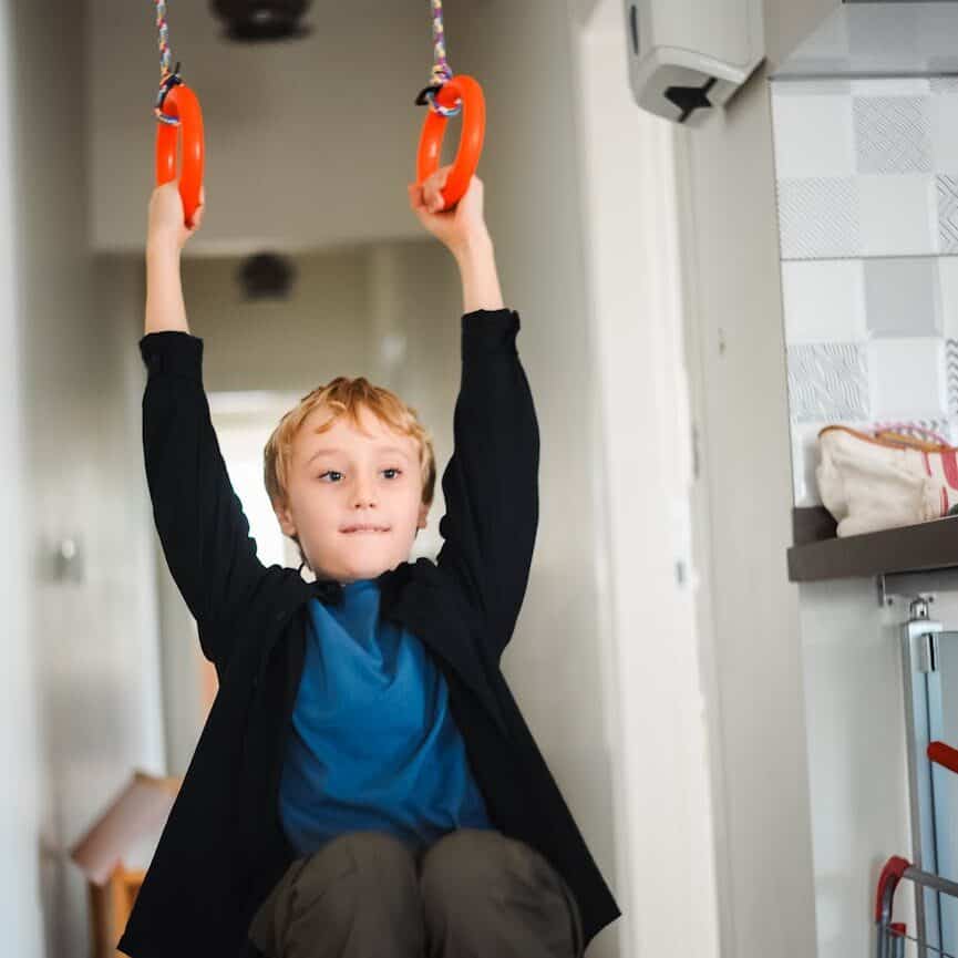child swinging indoors on gymnastic rings